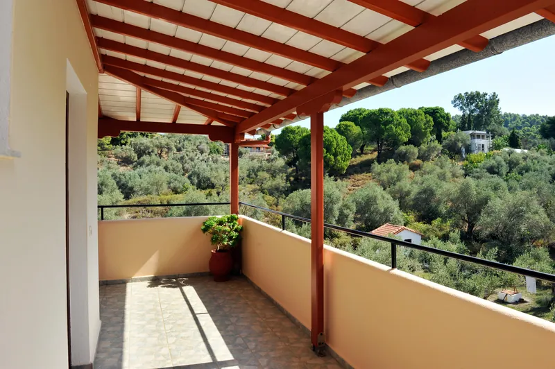 A balcony under the red pergola, looking over the olive trees