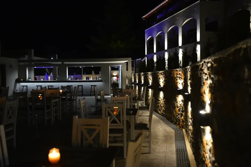 Φωτισμένα τραπέζια δίπλα στον πέτρινο τοίχο του Esurio
